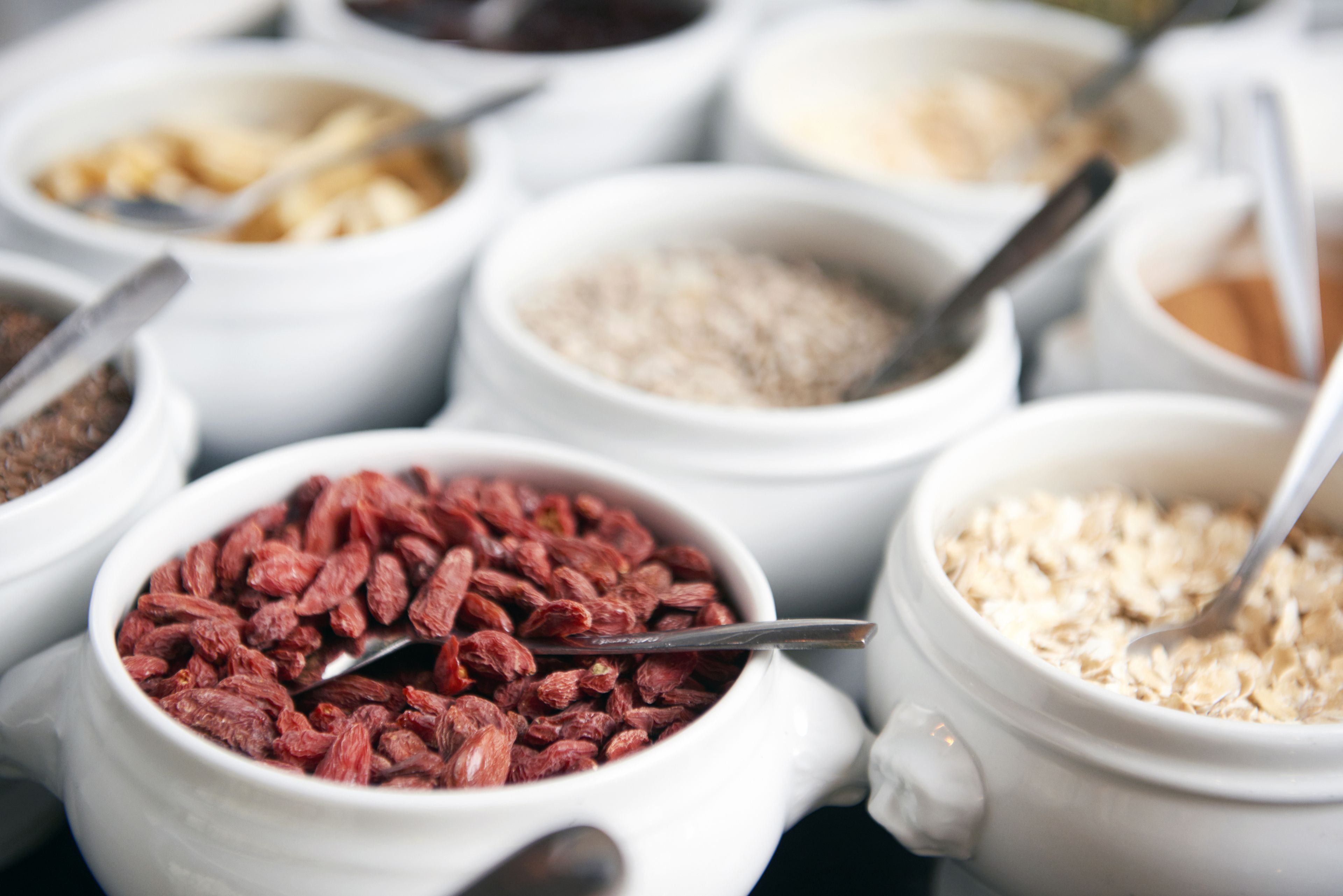 Diversos alimentos en cuencos blancos con cucharas.