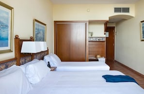 A hotel room with two beds, a wooden wardrobe, a bathroom with a sink and mirror, and a small balcony. - Hotel Roses Platja (Roses)