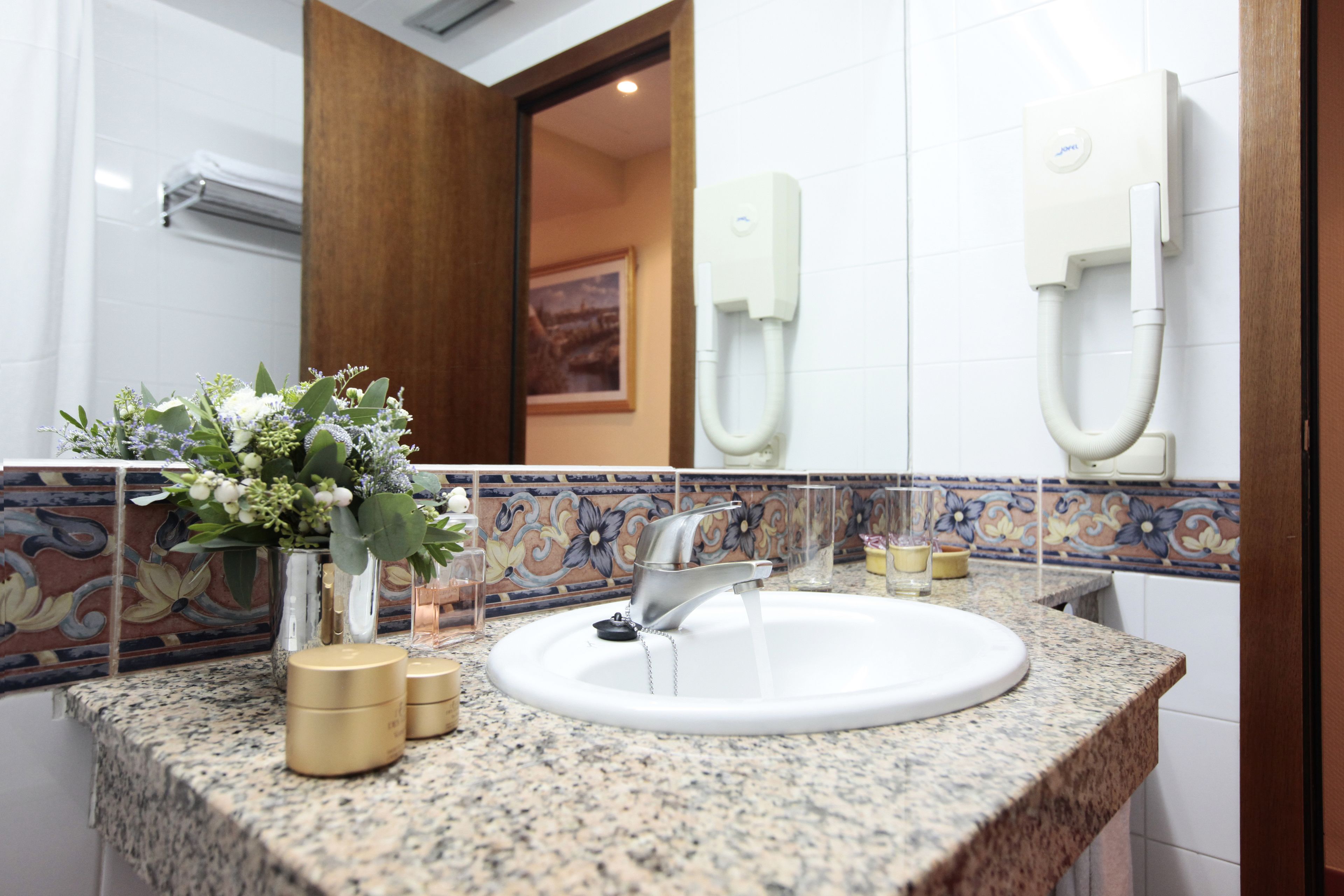 A bathroom with a granite countertop, a white sink, a mirror, and a wall-mounted phone.
