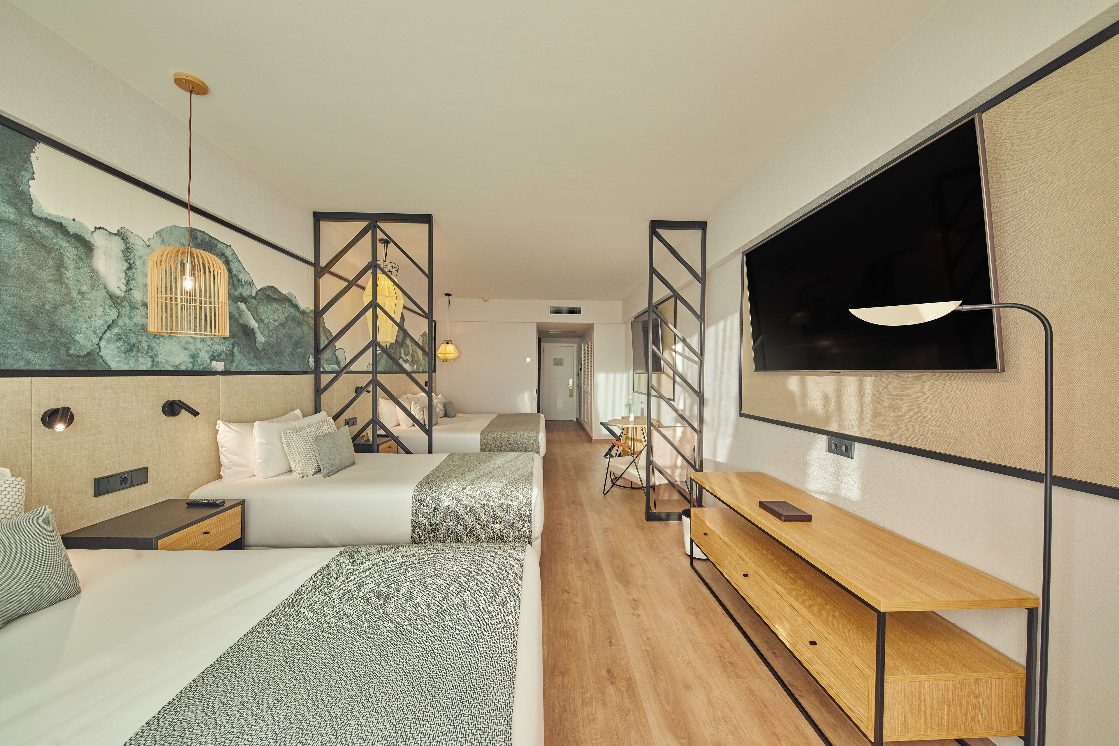Une chambre d’hôtel moderne avec un grand lit, un bureau, une télévision et une fresque murale.