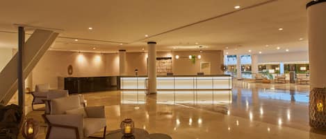 A spacious lobby with a reception desk, seating area, and a staircase.