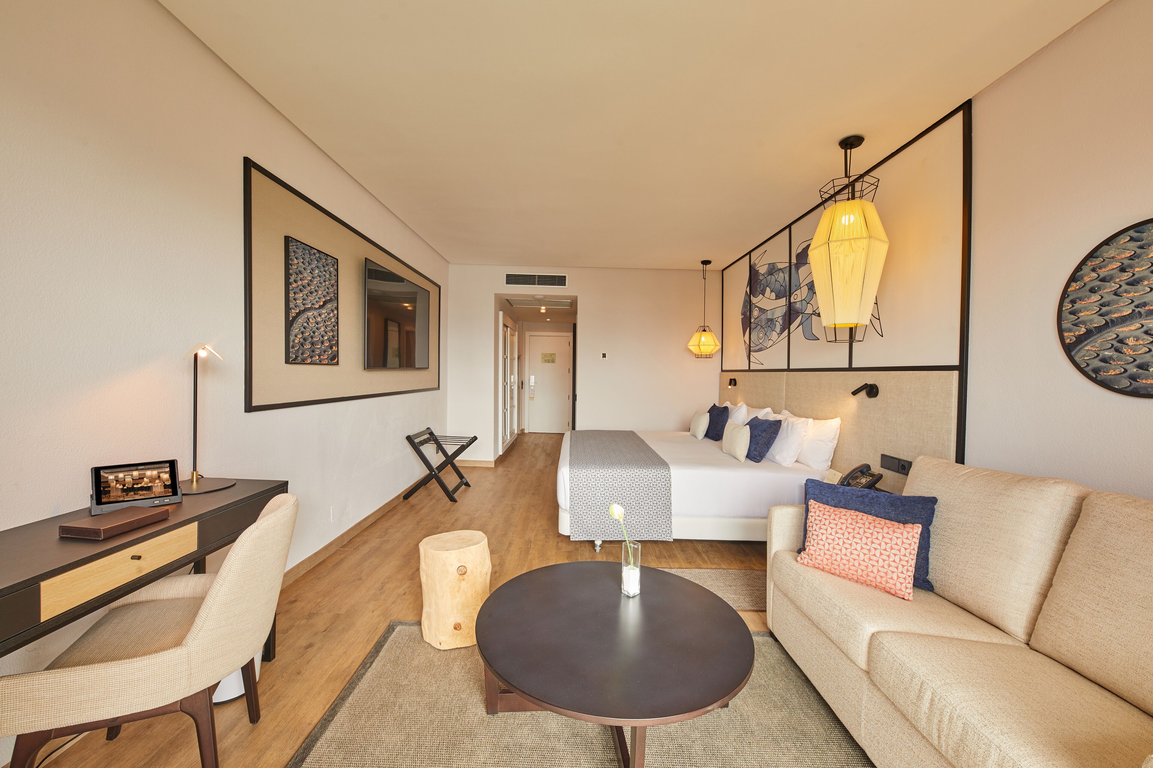 Ein modernes Hotelzimmer mit Bett, Sofa, Schreibtisch und einem kleinen Tisch.