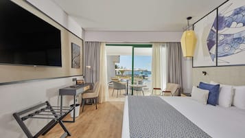 Habitación de hotel con cama, escritorio, silla y vistas a la piscina y al área exterior.