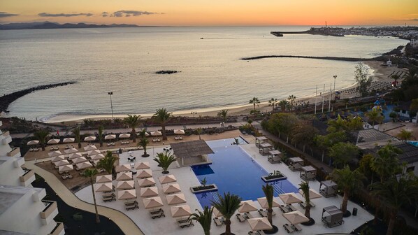 A resort with a large pool, sun loungers, and a view of the sea at sunset. - Grand Hyatt Lanzarote Playa Dorada Resort (Yaiza)