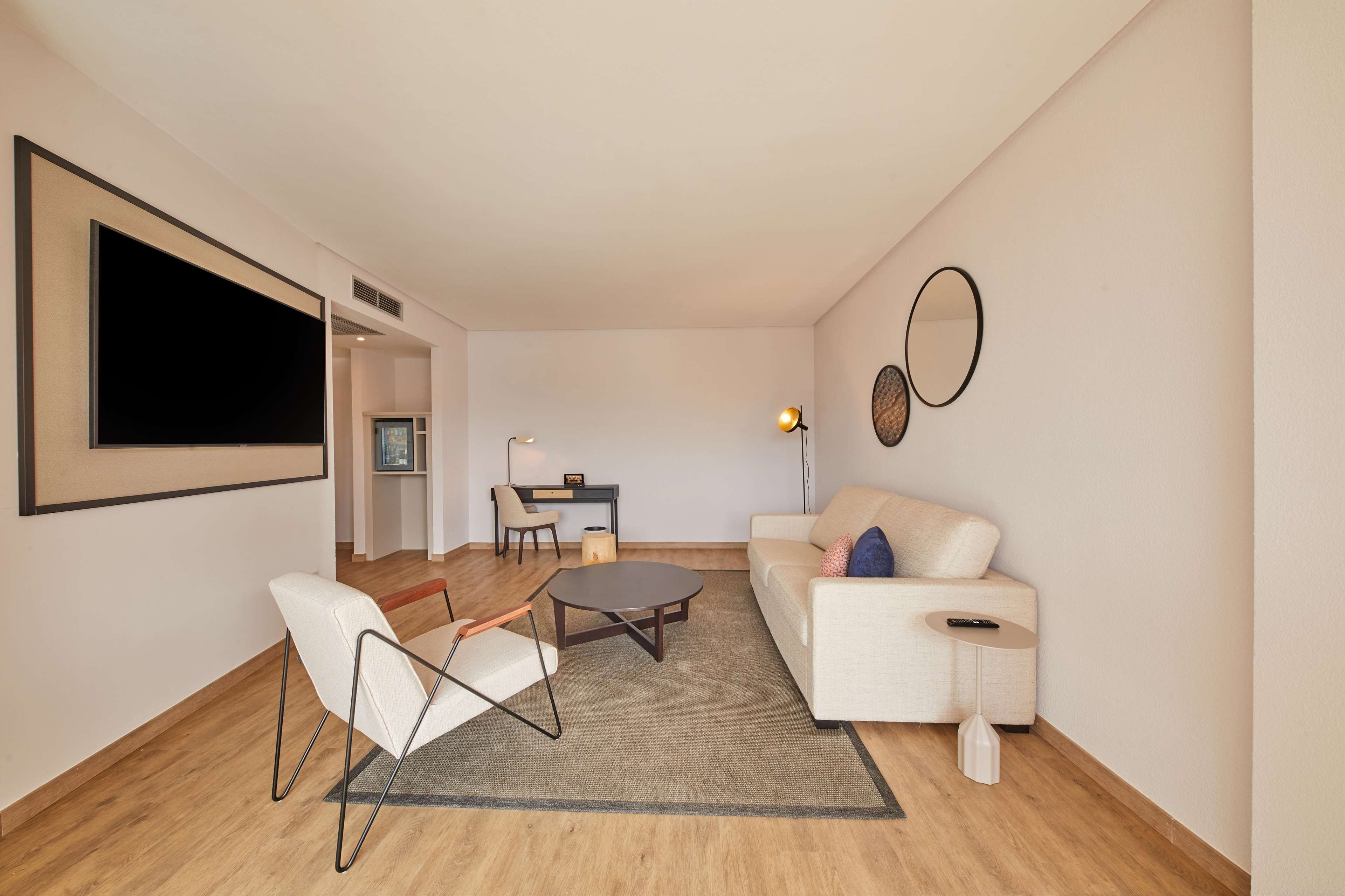 Una sala de estar moderna con un sofá, una silla, una mesa de centro y un escritorio con una silla.