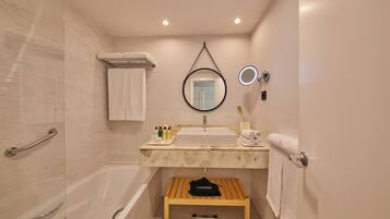 Un baño con bañera, lavamanos, espejo y toallero.