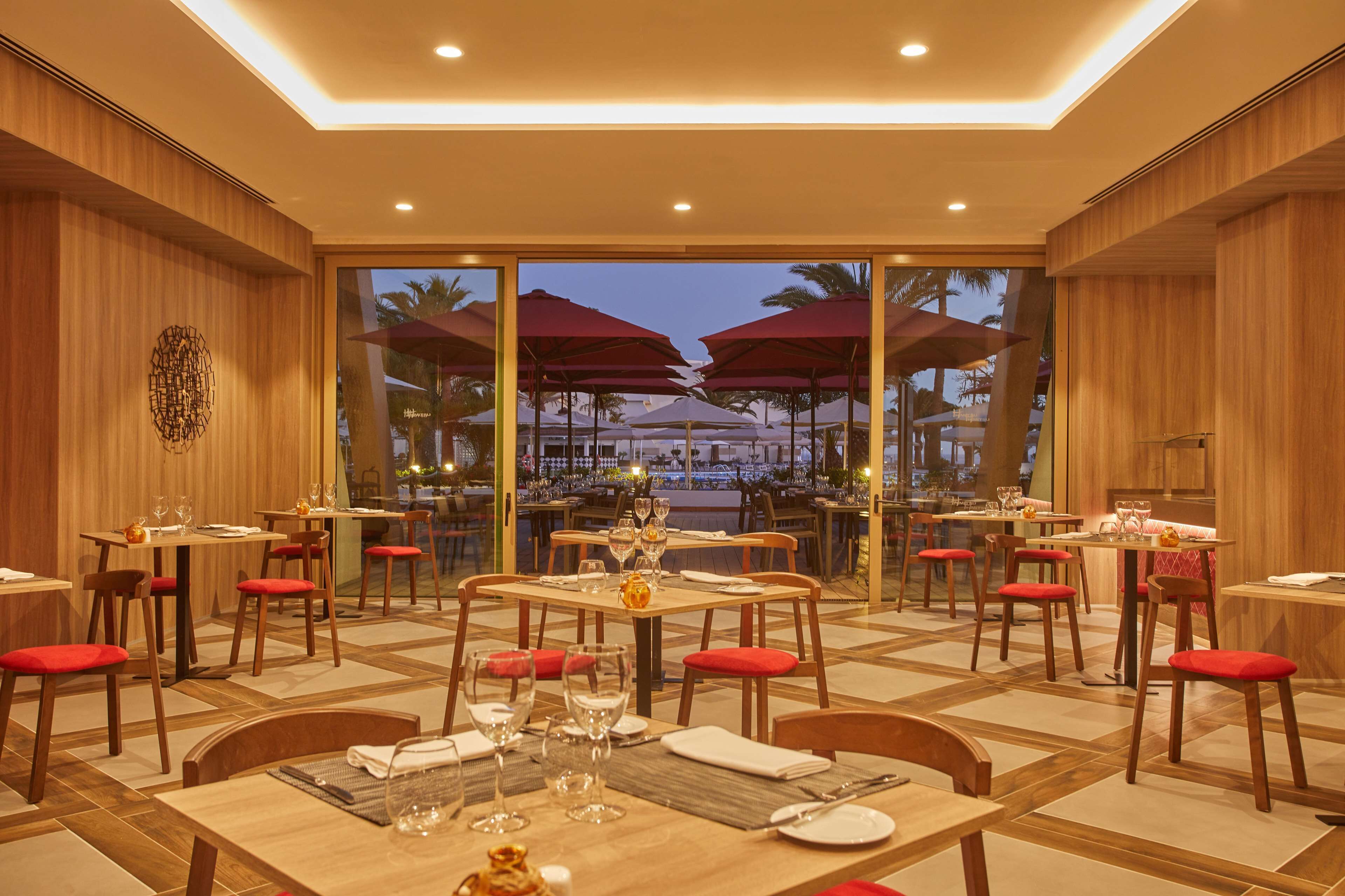 Un restaurant aux murs en bois, aux chaises rembourrées de rouge et aux tables dressées pour le repas.