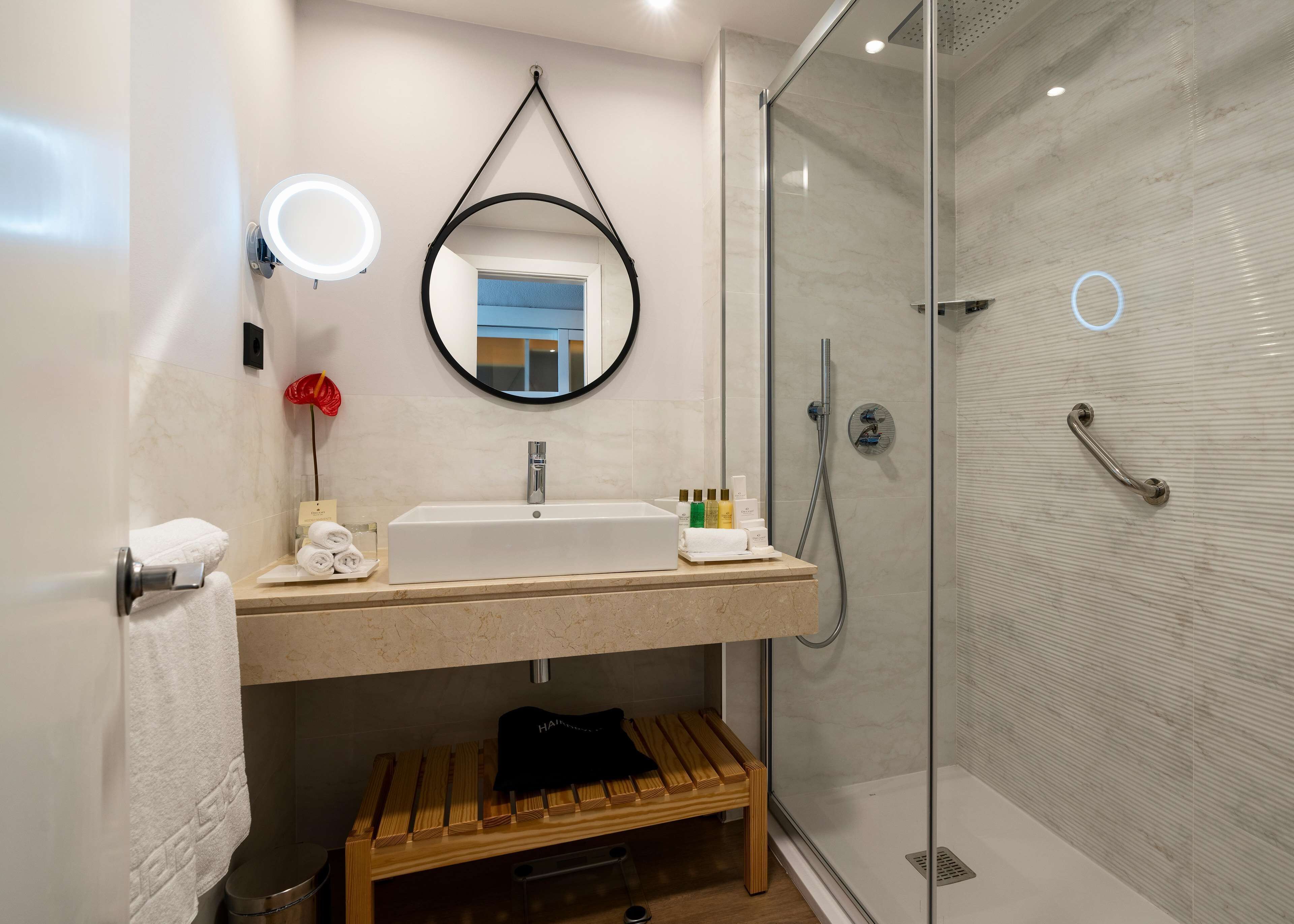 A modern bathroom with a large mirror, a sink, and a shower.