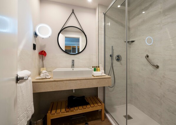 Une salle de bain moderne avec un grand miroir, un lavabo et une douche.