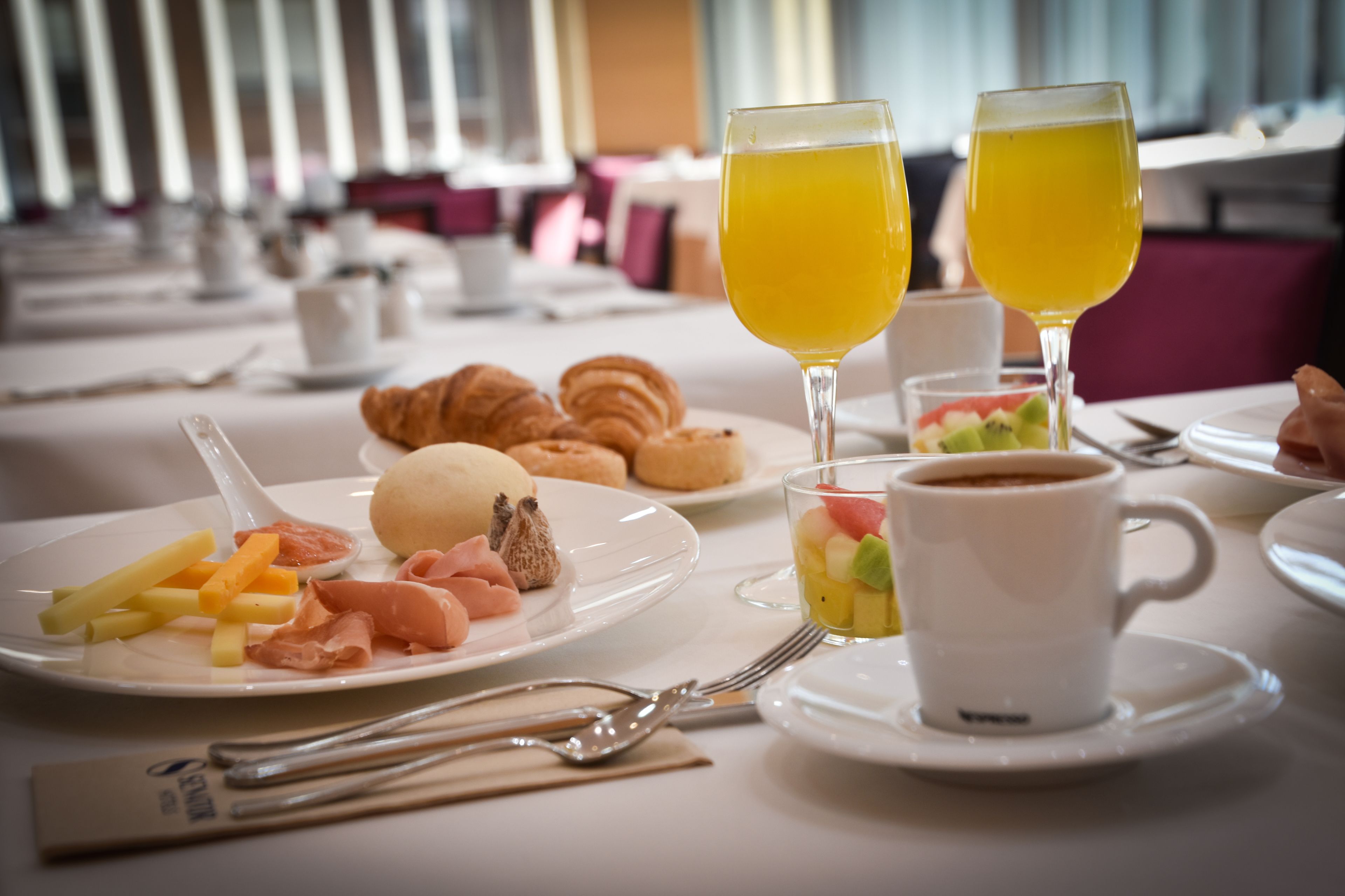 A breakfast setting with croissants, fruit, and coffee on a table.