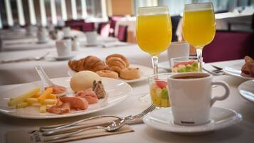 Un desayuno con croissants, fruta y café sobre una mesa.