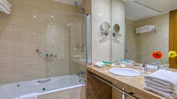 Un baño moderno con ducha envuelta en vidrio, lavamanos y tocador con toallas.