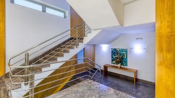 A modern interior with a marble staircase, a wooden bench, and a wall-mounted artwork.