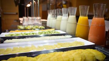 Un bufé con diversas frutas y bebidas.