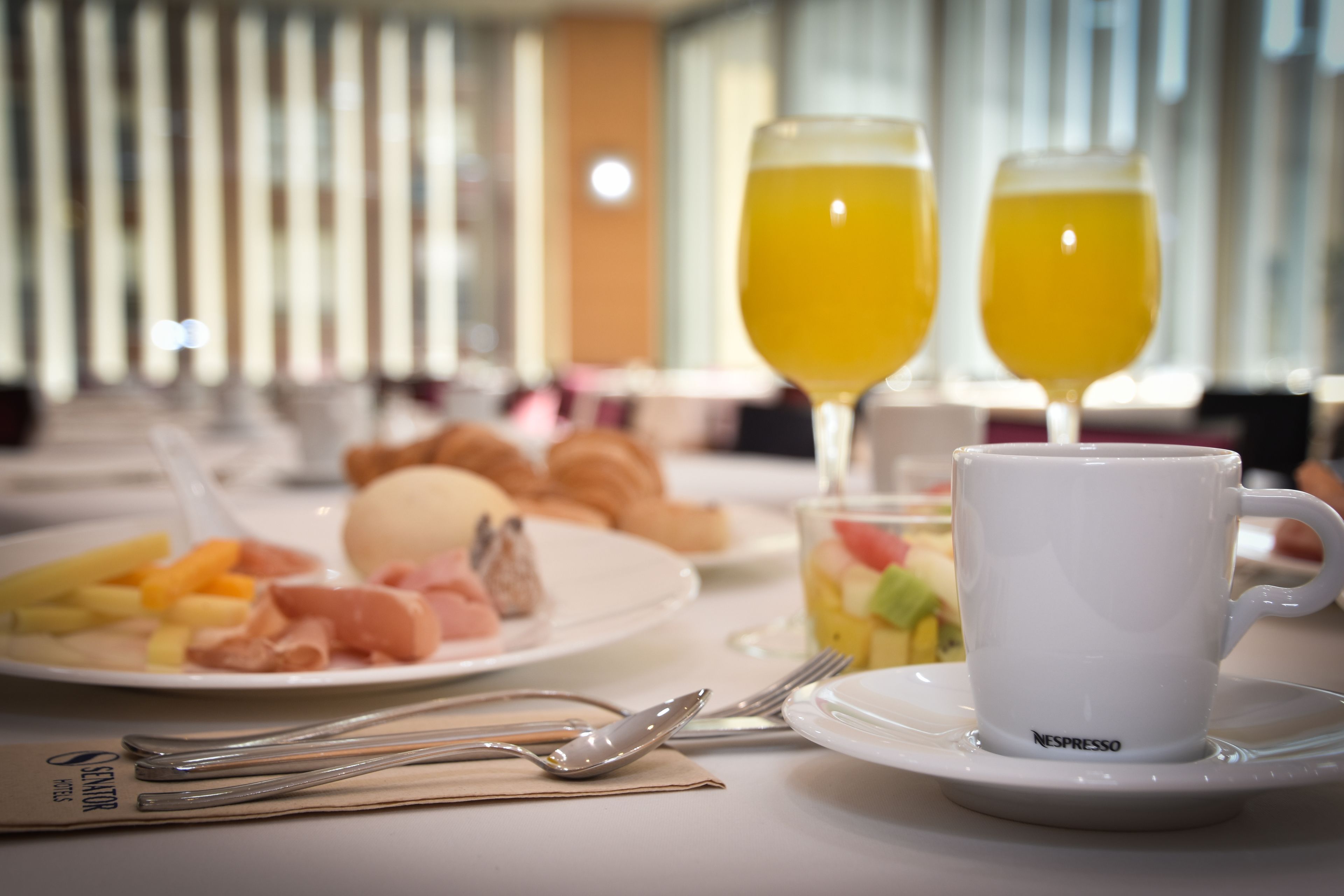 A breakfast setting with plates of food, a cup of coffee, and two glasses of orange juice.