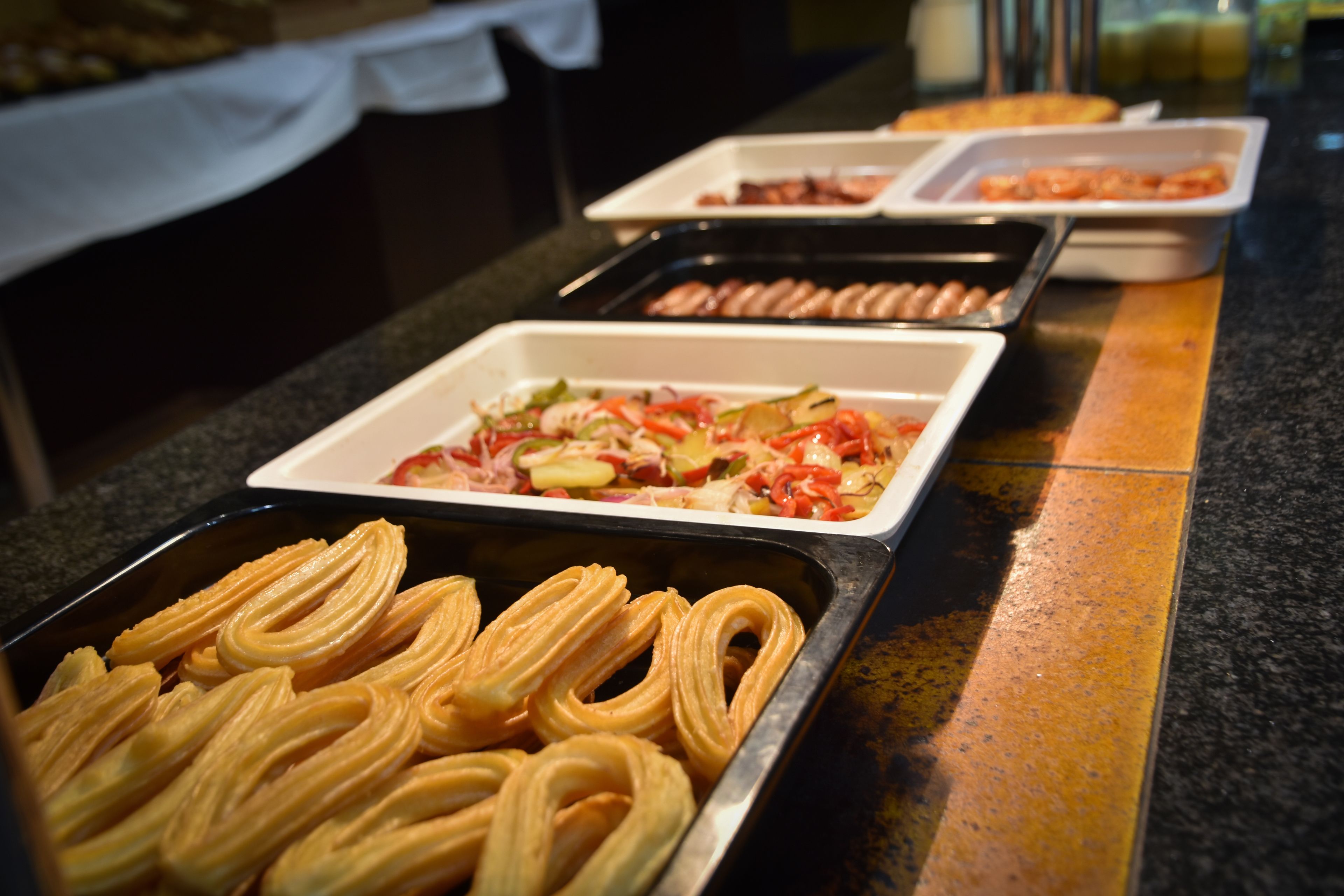 A buffet with various food items including churros, a salad, and other dishes.