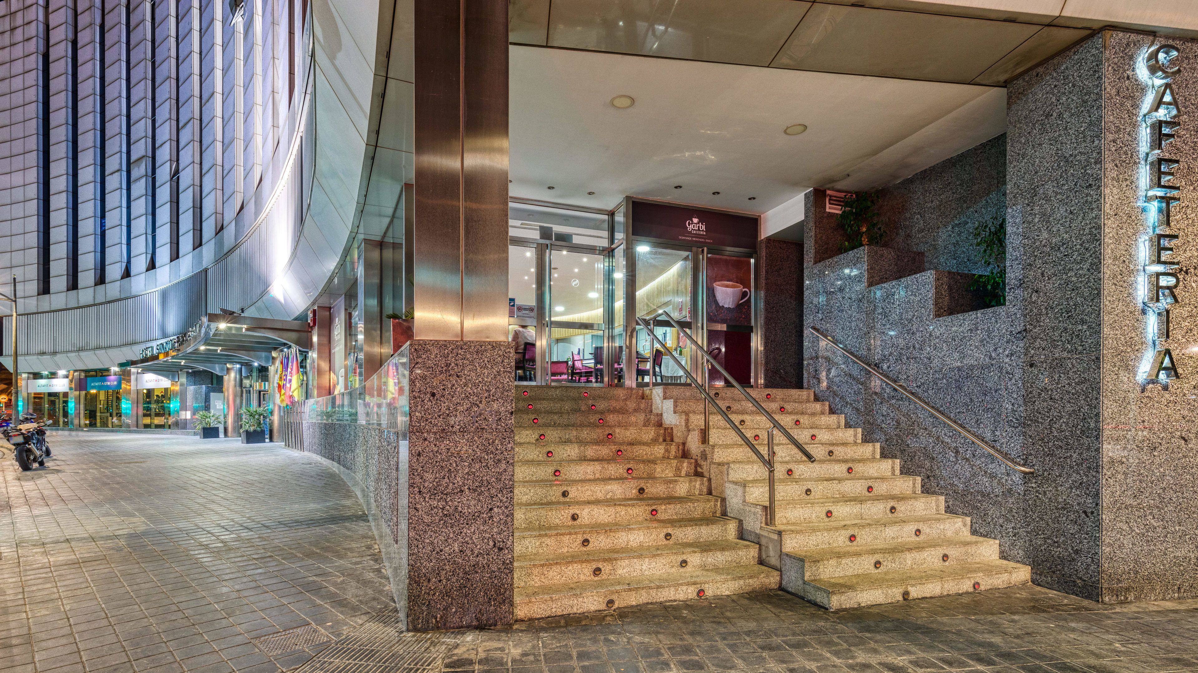 Vestíbulo de hotel con una escalera, una recepción y vistas al comedor interior.