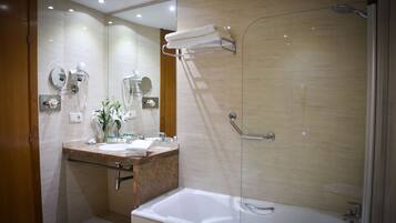 Un baño moderno con un espejo grande, un lavabo, una bañera y una ducha con mampara de vidrio.