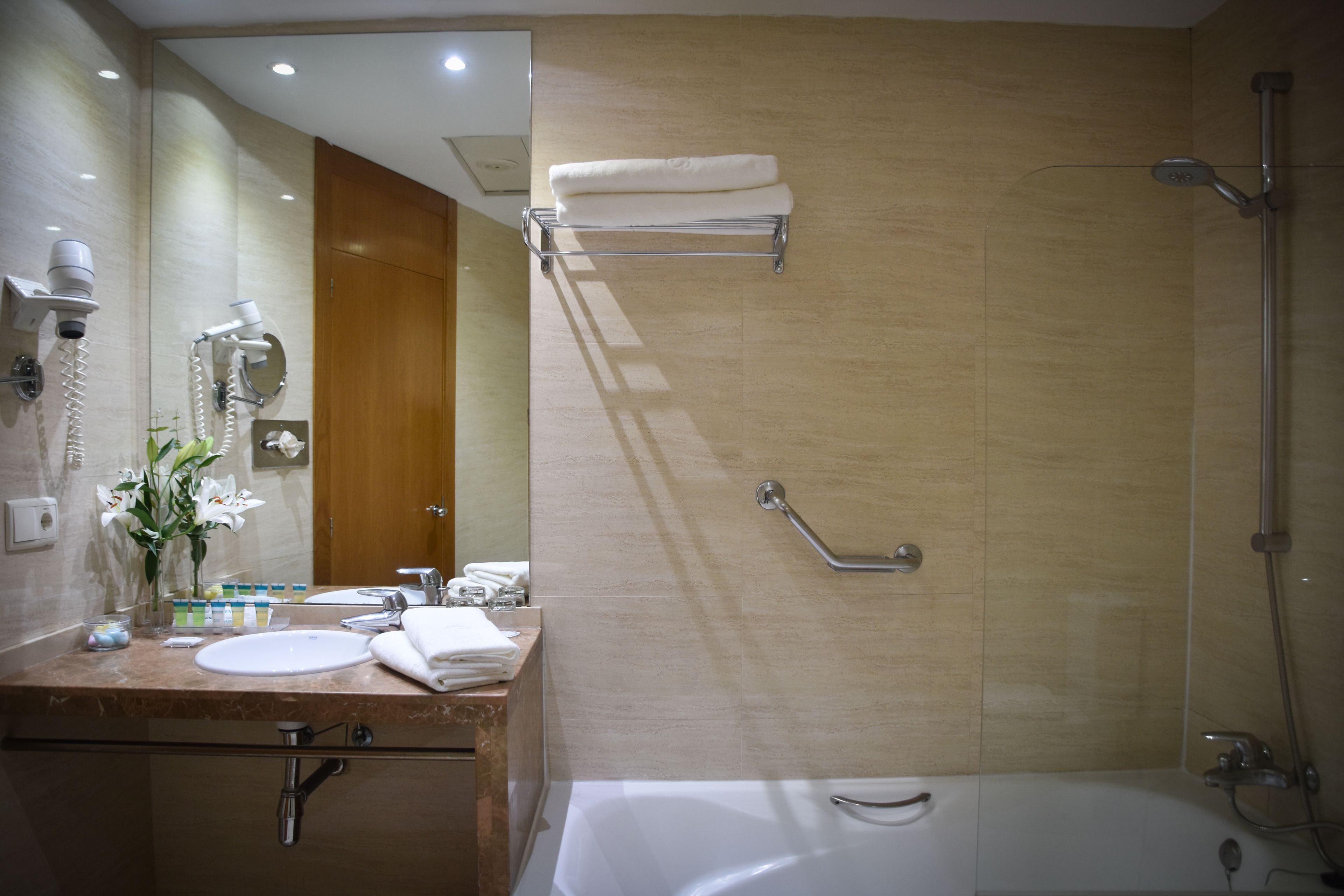 Une salle de bain moderne équipée d’un lavabo, d’un miroir, d’un porte-serviettes et d’une douche.