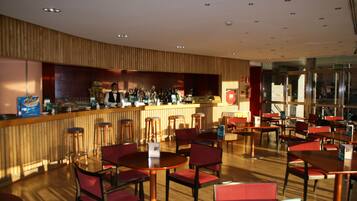 Un restaurante moderno con paneles de madera, una zona de bar y sillas y mesas rojas.