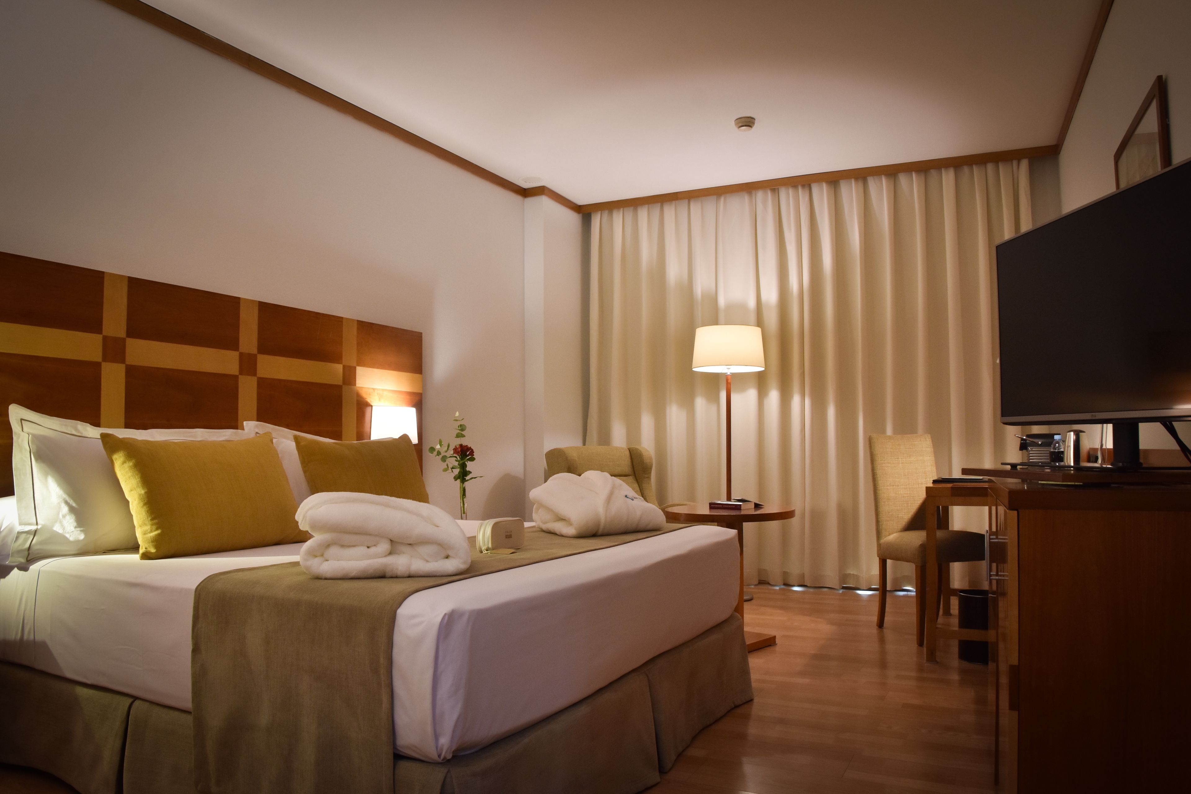 Ein Hotelzimmer mit Bett, Schreibtisch, Stuhl, Fernseher und Lampe.