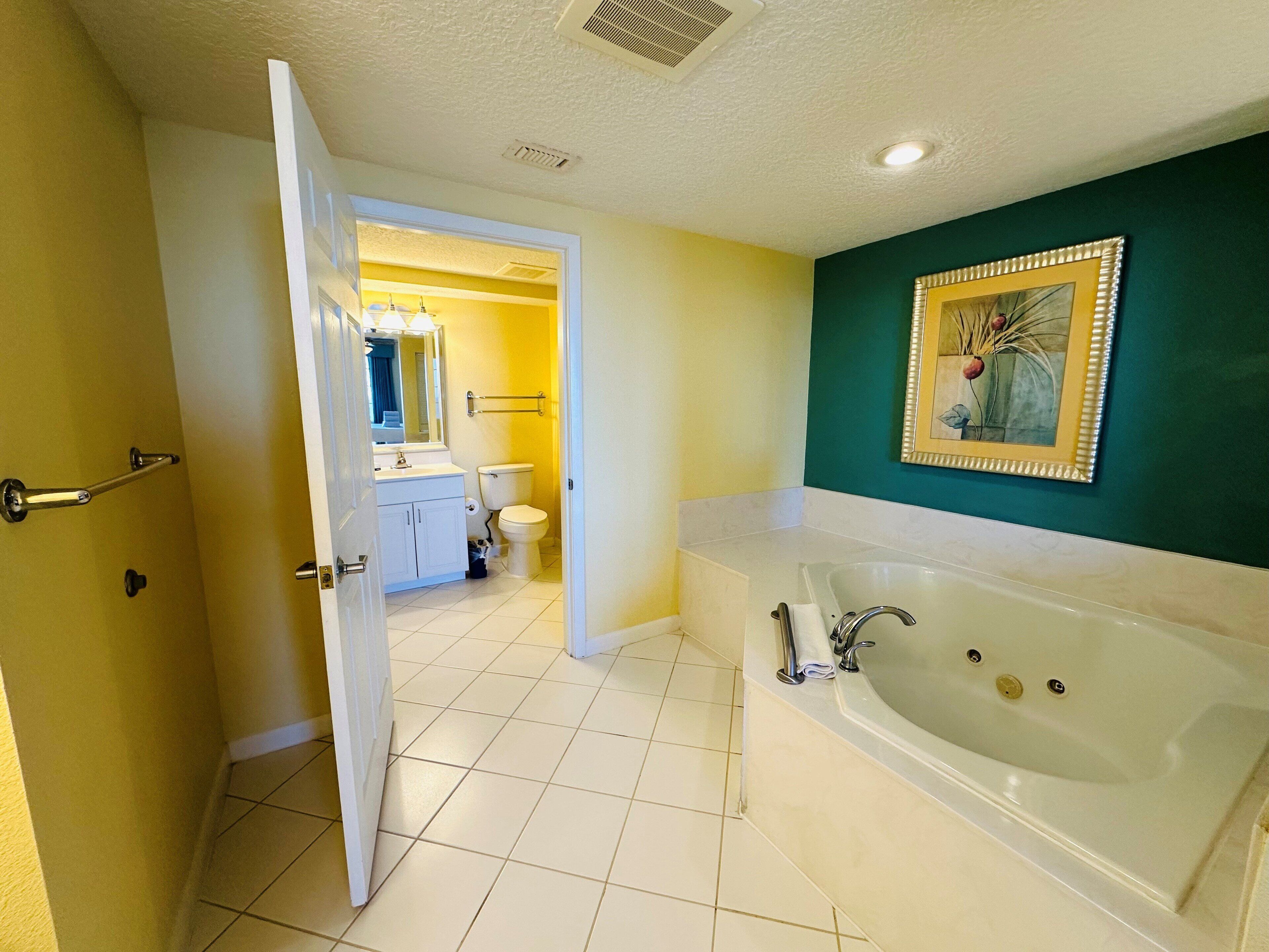 A bathroom with a large bathtub, a toilet, and a sink.