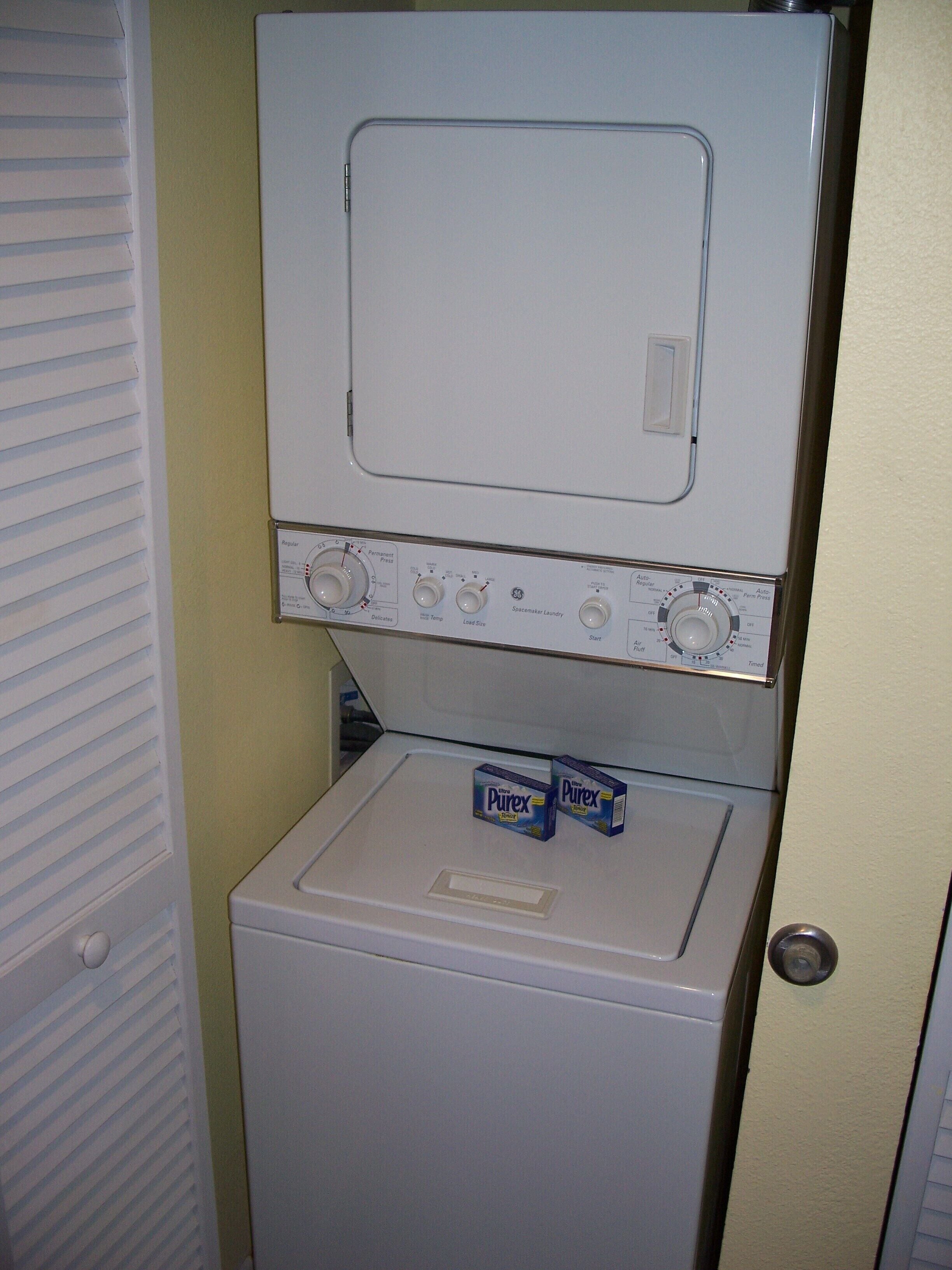 Una lavadora de carga frontal con un panel de control y dos cajas de detergente Purex encima.