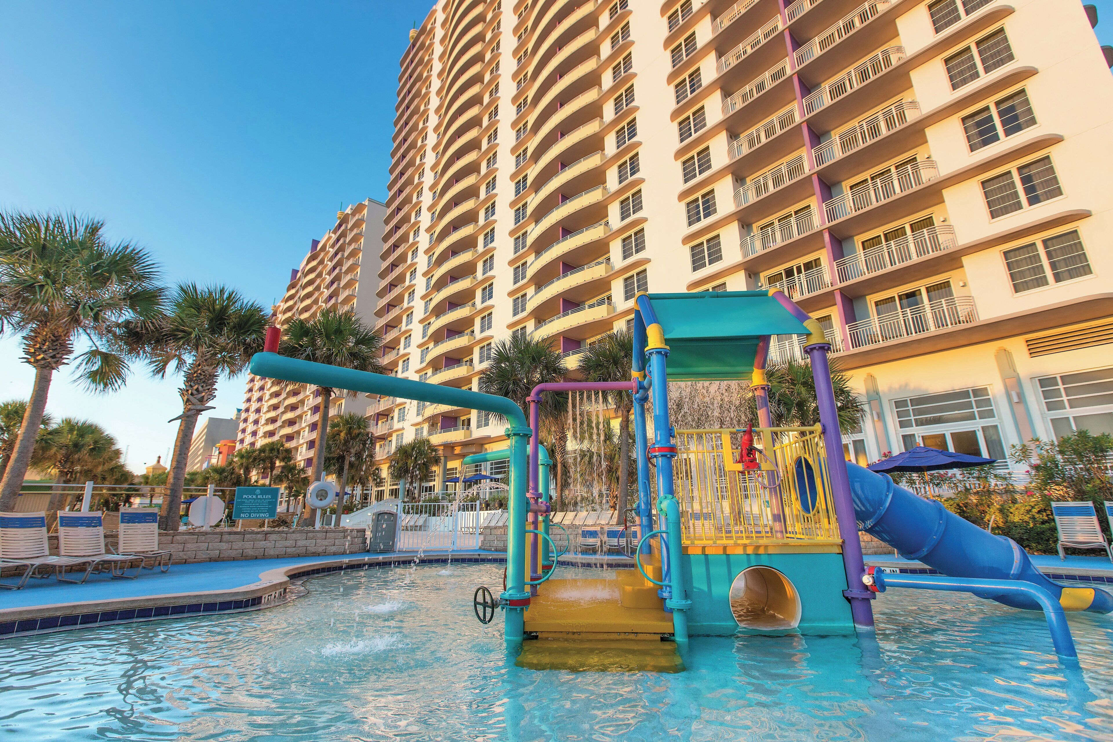 A water park with slides and a pool, surrounded by tall buildings.