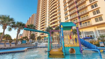 A water park with slides and a pool, surrounded by tall buildings.