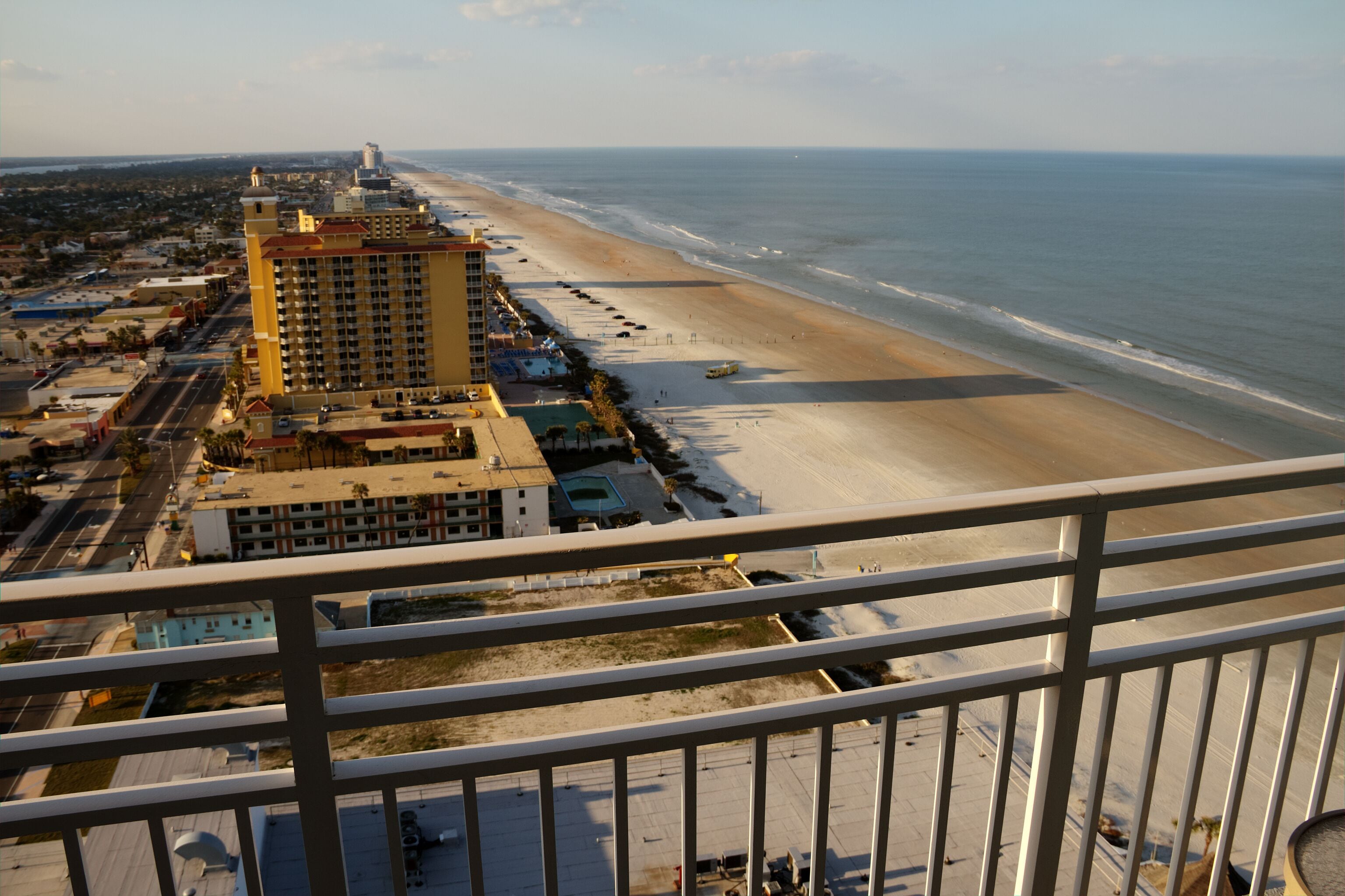 A high-rise hotel overlooking a beach with a clear view of the ocean and a sandy shoreline.