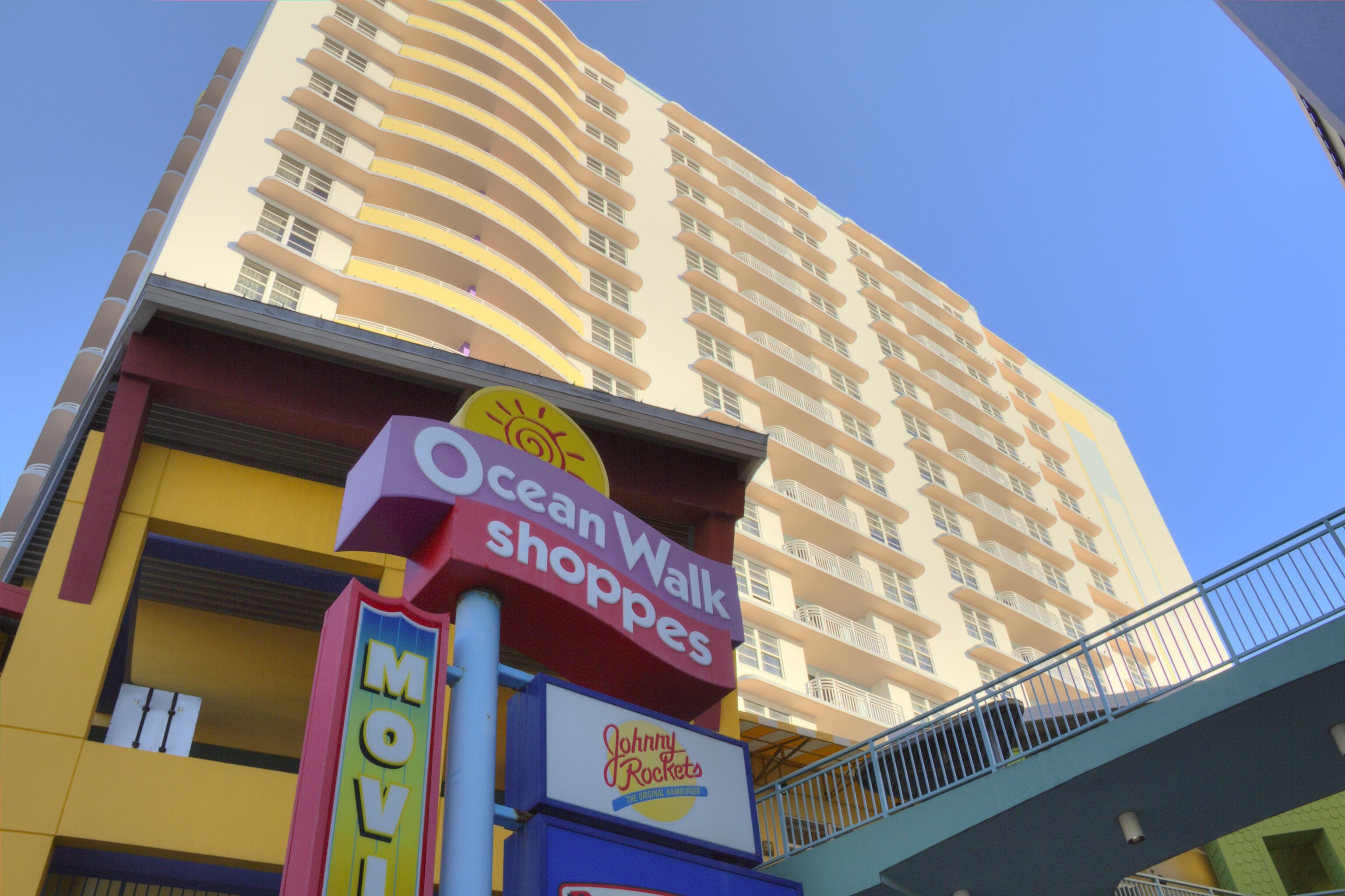 A multi-story building with a sign for Ocean Walk Shops and a sign for Johnny Rockets.