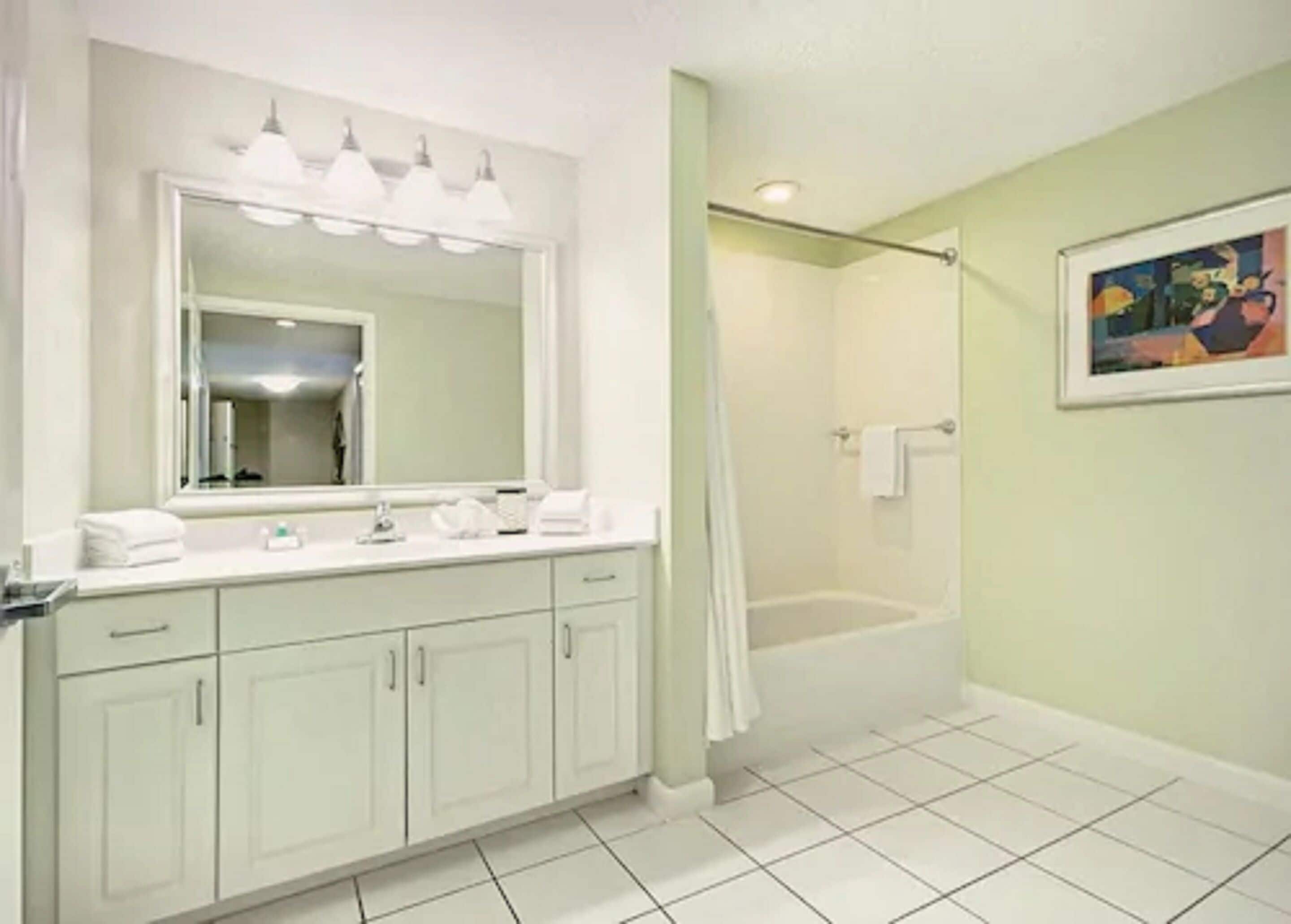 A bathroom with a white vanity, a large mirror, a shower with a glass door, and a bathtub.