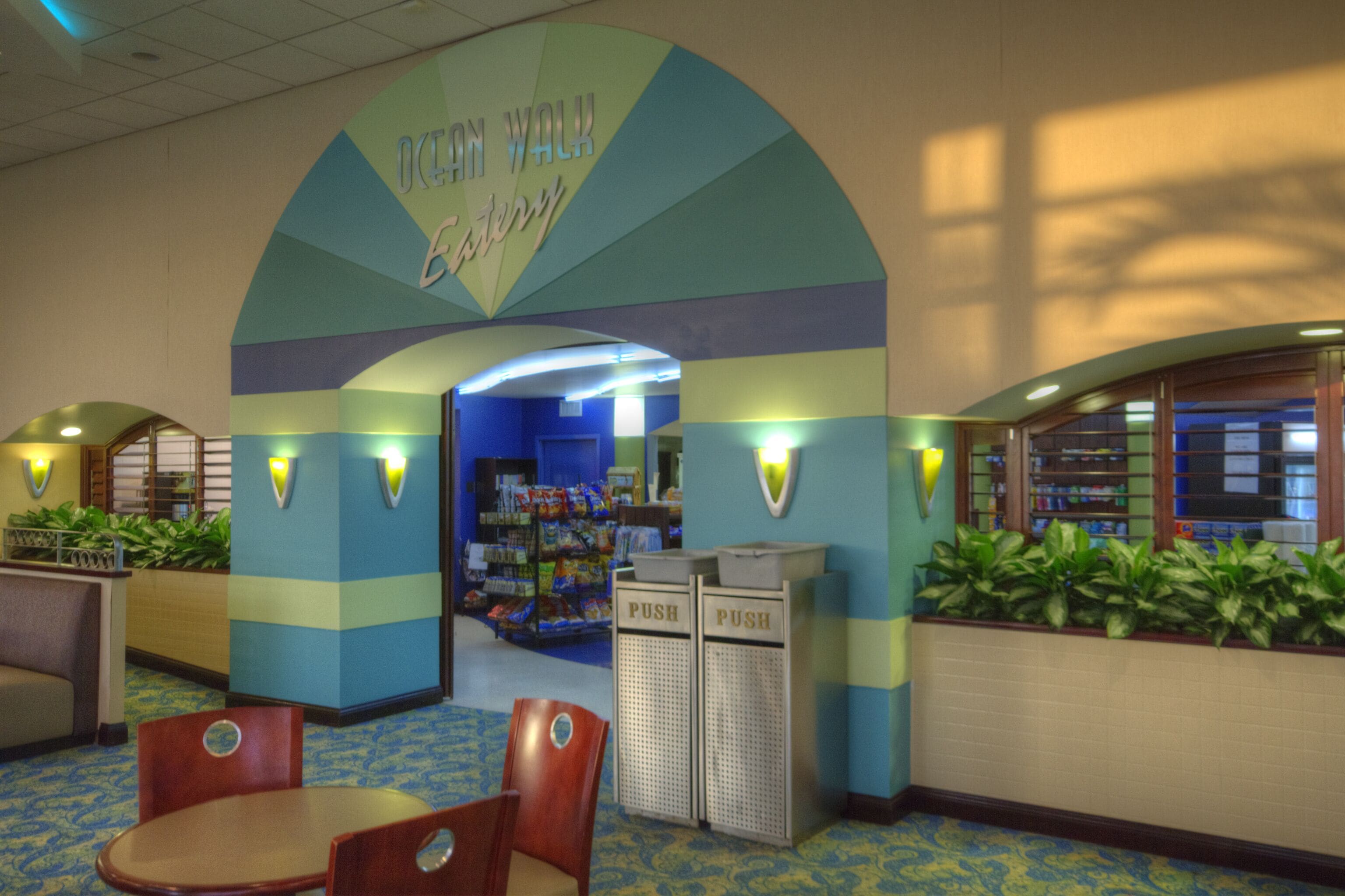 A lobby with a 'Ocean Walk' sign, seating area, and a snack bar.