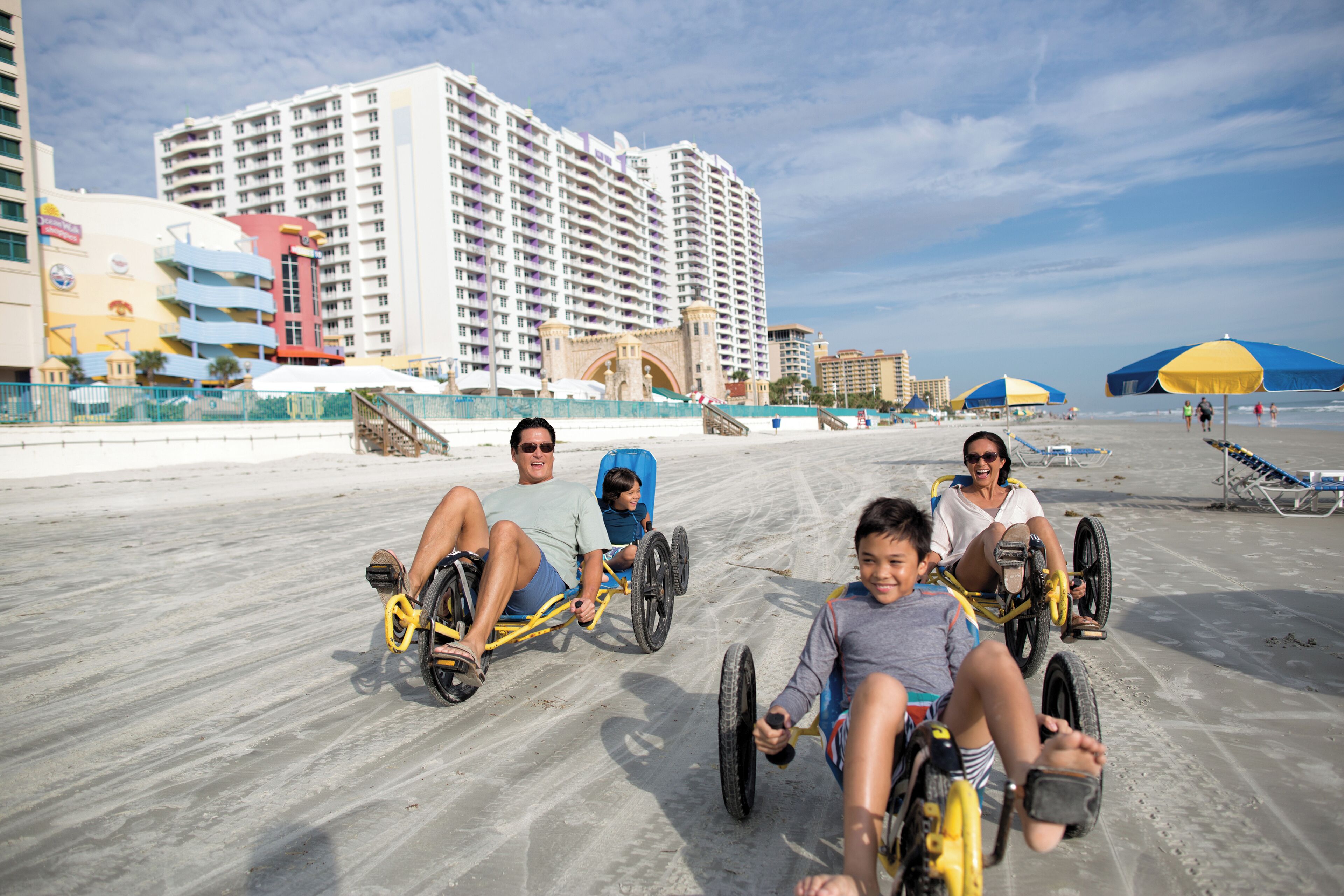 A sandy beach with people in wheelchairs and a wheelchair racer.