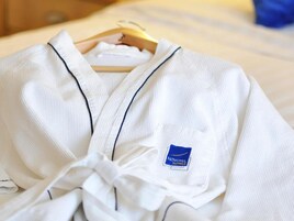 A white robe with a blue logo on a wooden hanger.