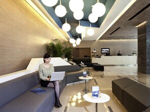 A modern lobby with a reception desk, seating areas, and a large plant. - Novotel Shenzhen Watergate (Shenzhen)