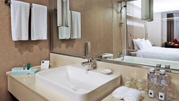 A hotel bathroom with a large sink, a mirror, and a shower.
