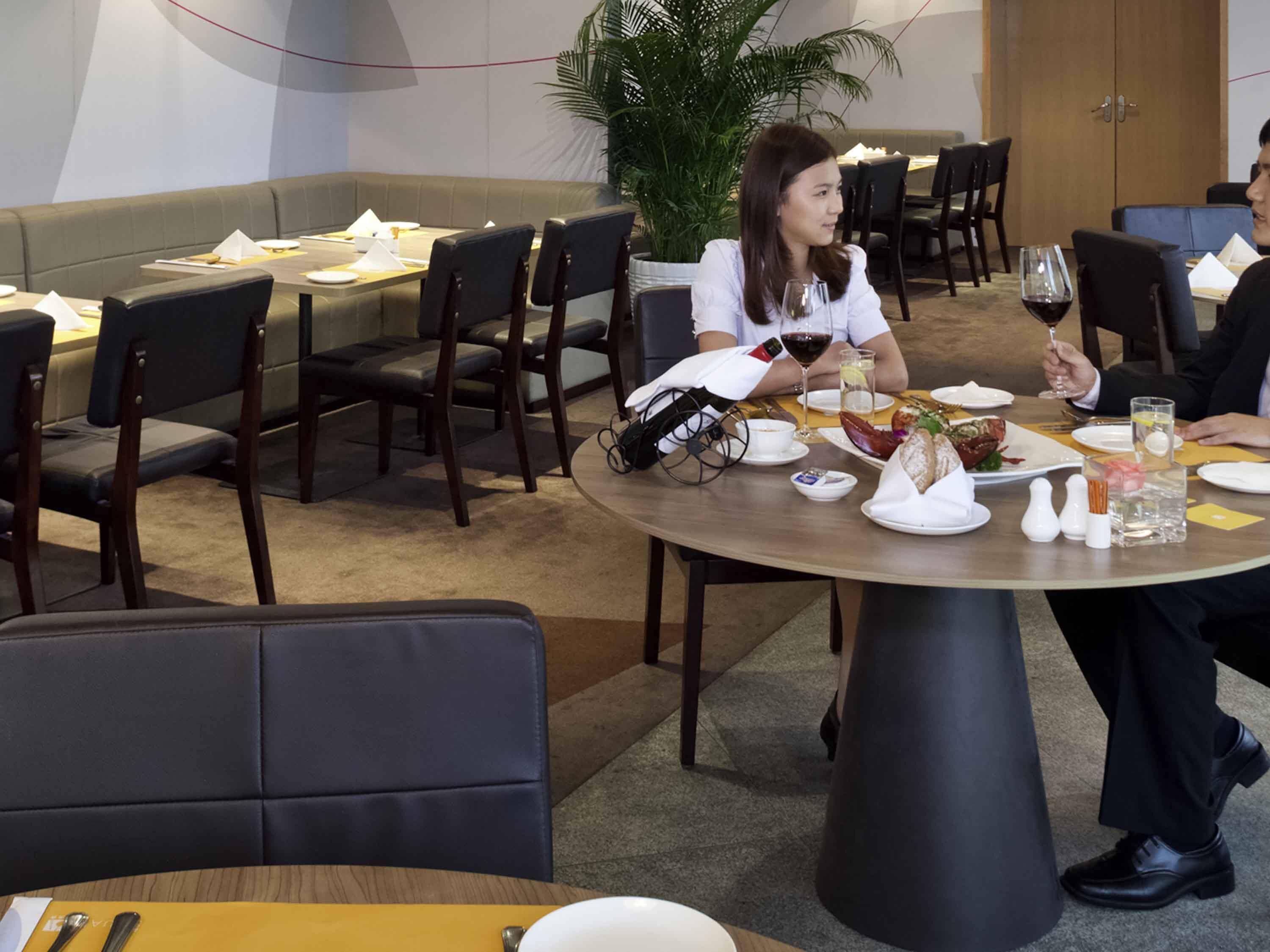 Un comedor con mesas redondas, sillas y una planta en maceta.