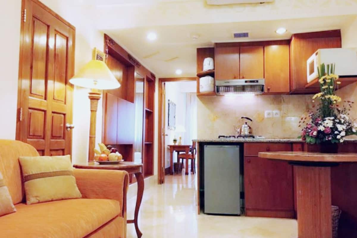 Un espacio habitable funcional con sofá, mesa de comedor, zona de cocina con refrigerador y armarios de madera.