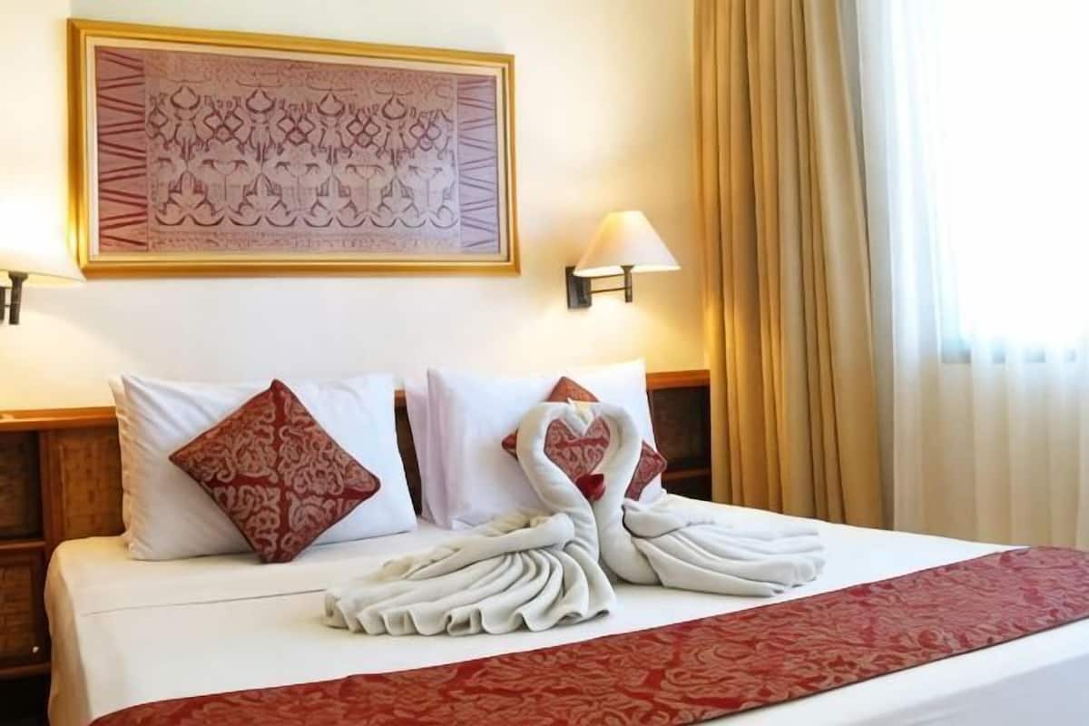 Habitación de hotel con una cama bien hecha, un adorno en la pared y una ventana con cortinas.