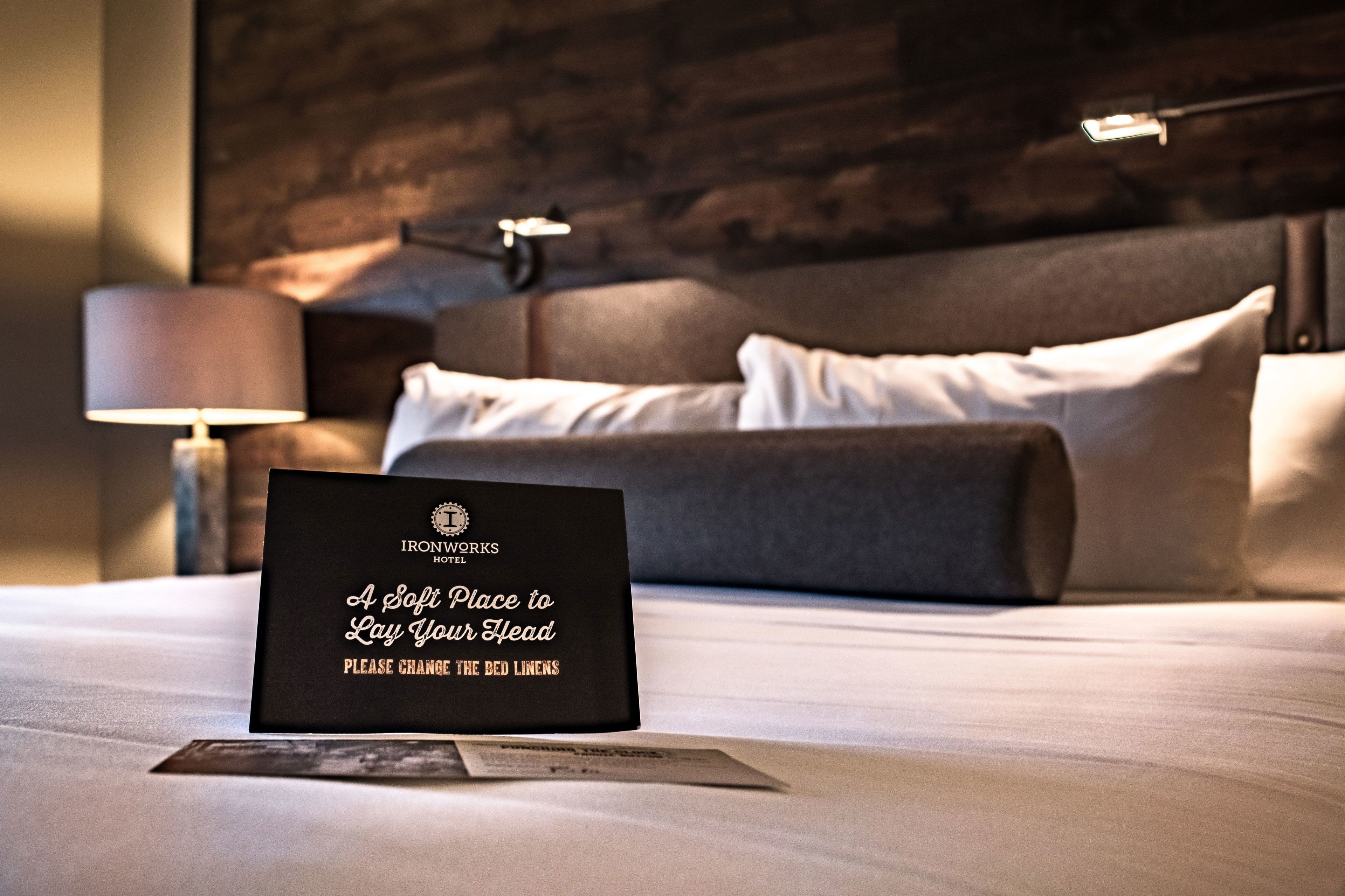 En väl bäddad säng med en skylt som anger hotellets namn och en önskan om att få sängkläderna bytta.