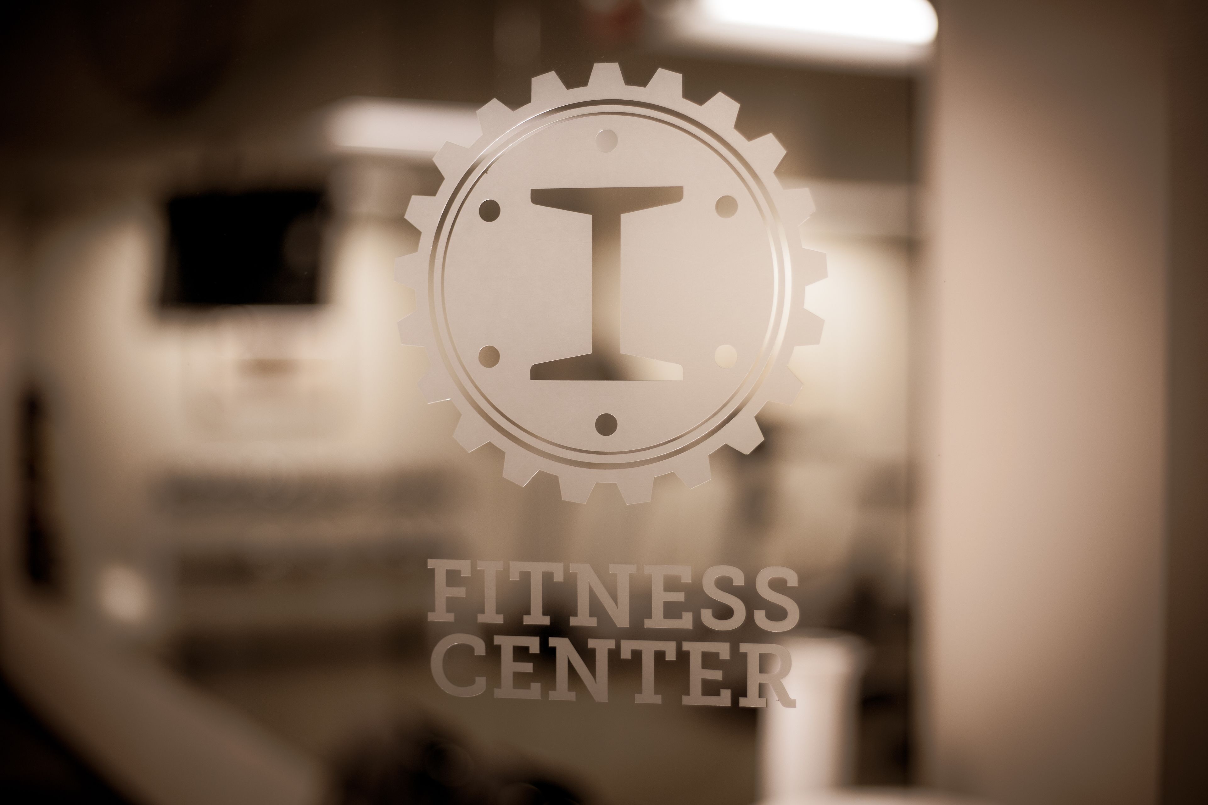 Ein verschwommenes Logo mit dem Text "FITNESS CENTER" auf einer Glasfläche.