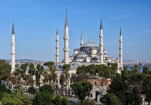 A large mosque with multiple minarets and domes, surrounded by trees and a view of the cityscape in the background. - 1207 Hotel Special Class - Sultanahmet (Istanbul)