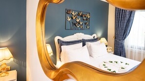 Una cama con sábanas blancas, cabecera, mesita de noche con lámpara y una obra de arte en la pared.