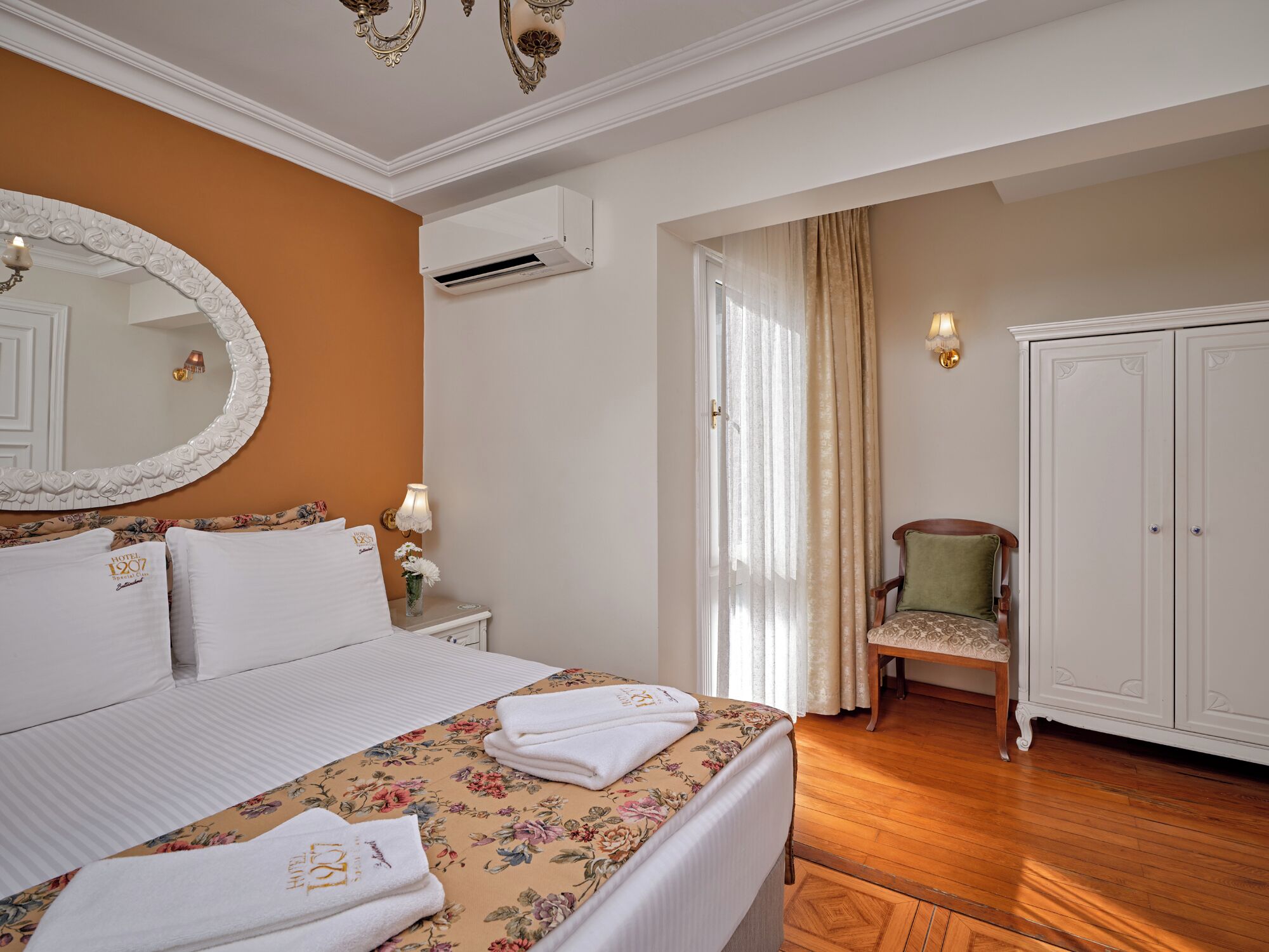 Una camera d'albergo con un letto, uno specchio, un condizionatore, una sedia e un armadio.