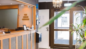 A reception desk with directional signs to the bar and restaurant, a telephone, and a digital display. - Sure Hotel by Best Western Algen (Östersund)
