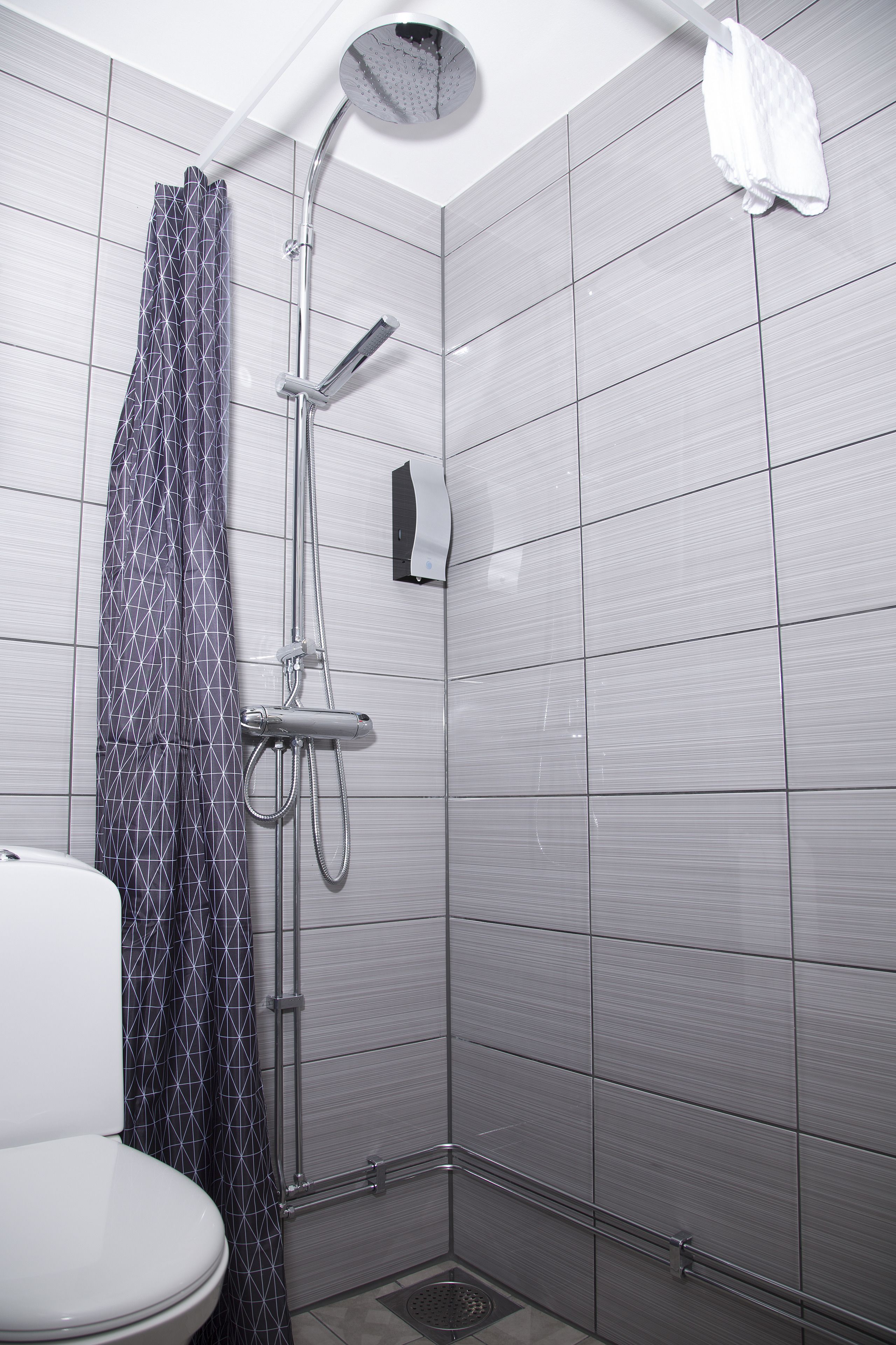 A bathroom with a shower, toilet, and tiled walls.