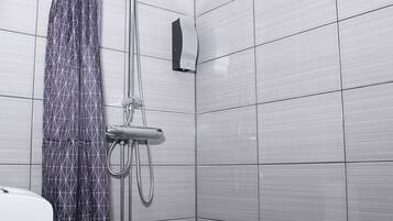 A bathroom with a shower, toilet, and tiled walls.