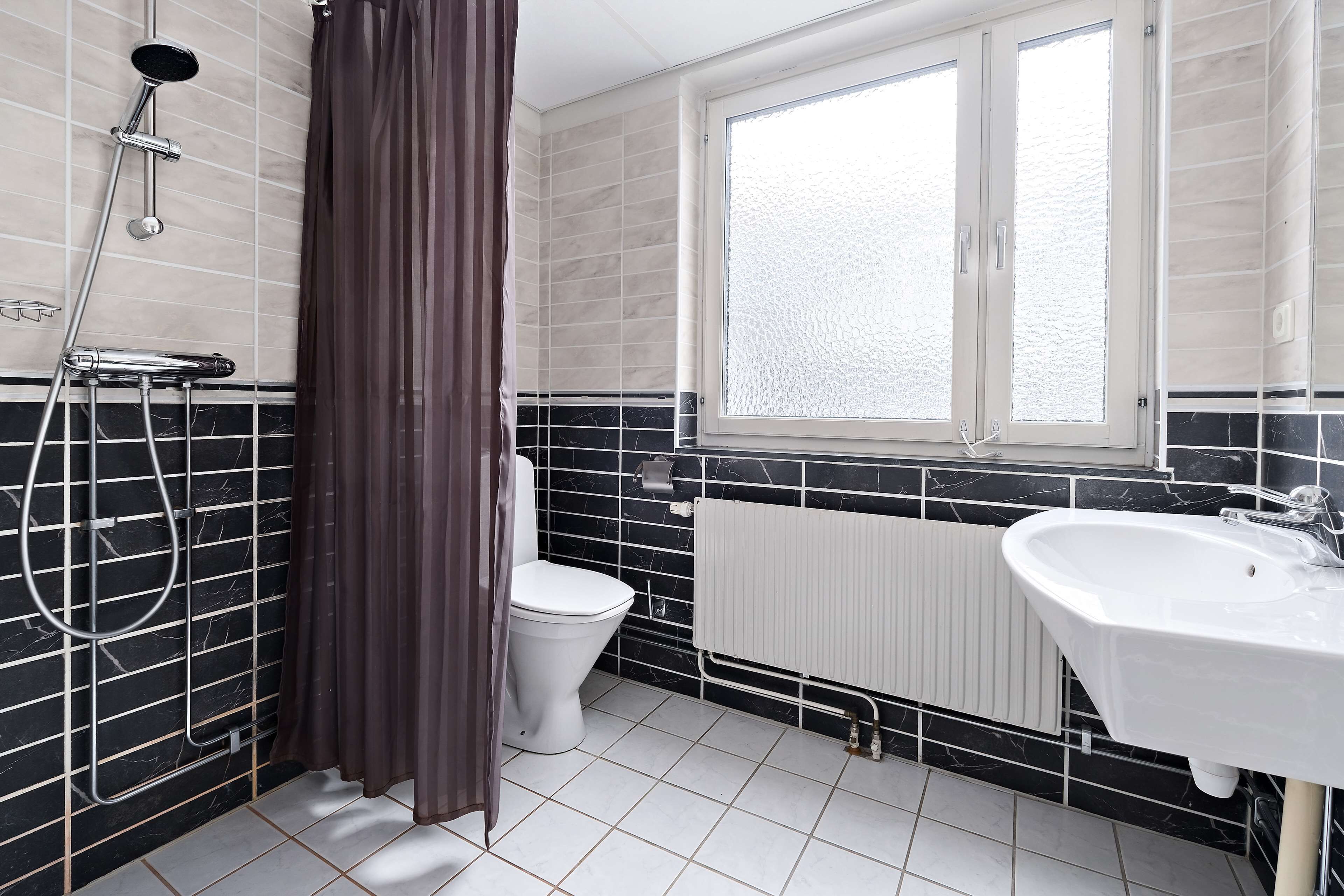 A bathroom with a shower, toilet, and sink.