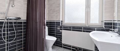 A bathroom with a shower, toilet, and sink.